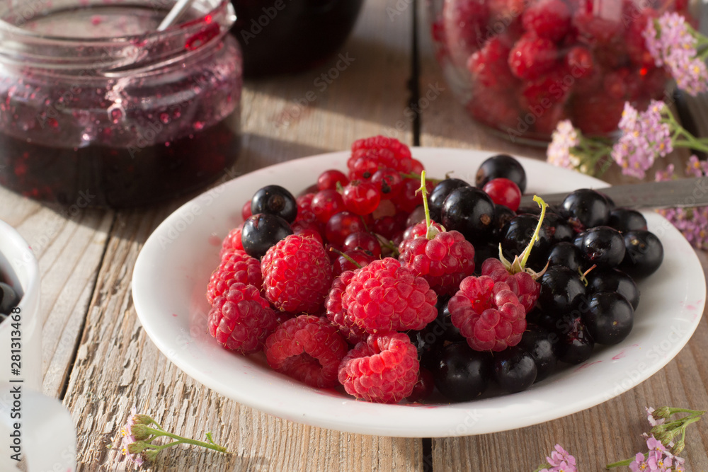 Raspberries, black and red currant on the plate and jam Raspberries, black and red currant on the plate and jam