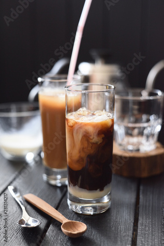 Beautiful swirls of coconut milk in Vietnamese iced coffee in tall glasses on dark background