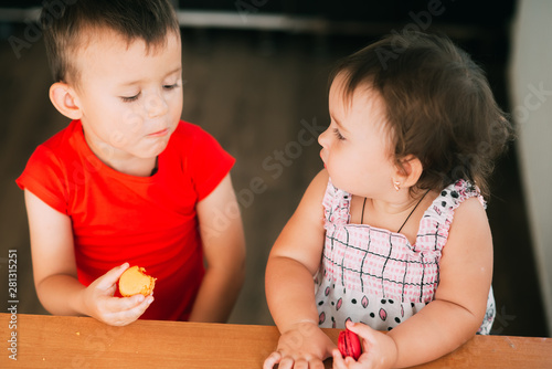 Kids boy and girl eating cake macaroons. Having fun brother and sister