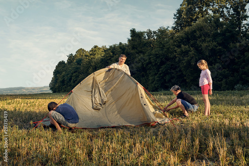 Family set up tent camp at sunset  beautiful summer landscape. Tourism  hiking and traveling in nature.