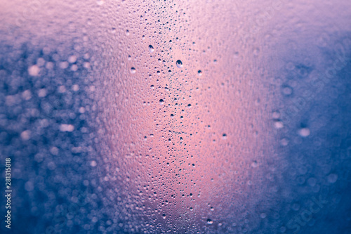 Drops on the window on a pink-blue background with a clear center and blurred bokeh