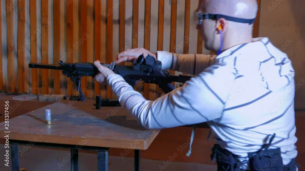 Shooter-man loading a twelve-gauge shotgun. A man trains in target shooting in an indoor shooting range using a high-caliber semi-automatic carbine Vepr-12. Shooter-man loading a twelve-gauge shotgun. A man trains in target shooting in an indoor shooting range using a high-caliber semi-automatic carbine Vepr-12.