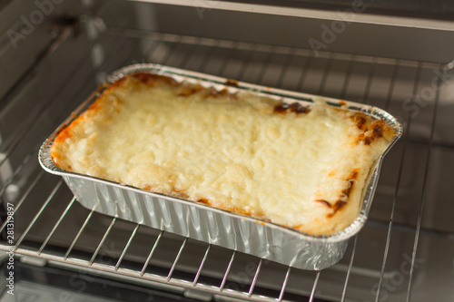 Cheese lasagna in a baking tray in the oven close-up. Process of baking lasagna. Cooking Italian food in a metalic container.