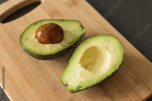Cut avocado on a oak wooden cutting board. Avocado cut into half. Healthy eating concept.
