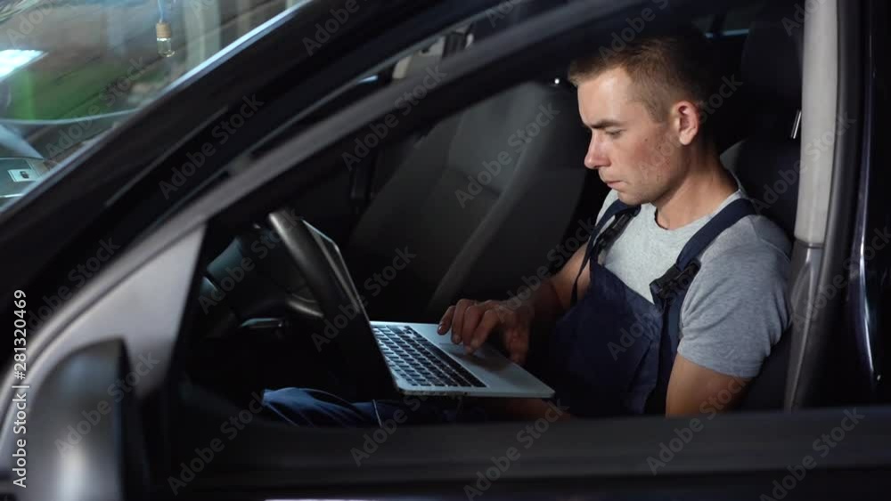 Car mechanic makes computer diagnostics in auto repair service Car mechanic makes computer diagnostics in auto repair service