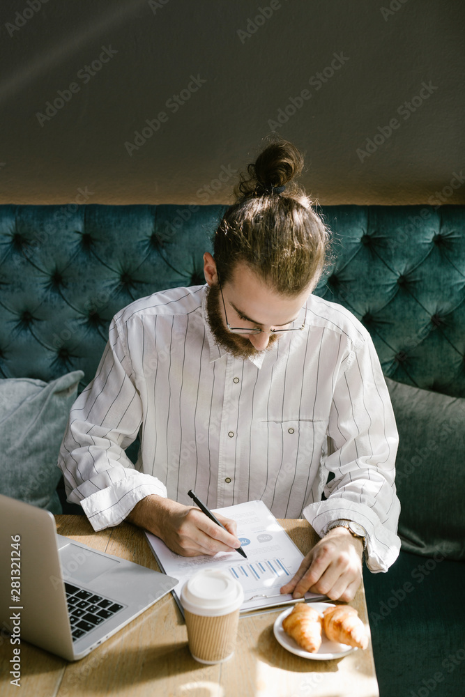 Serious businessman making notes in documents in cafe Serious businessman making notes in documents in cafe