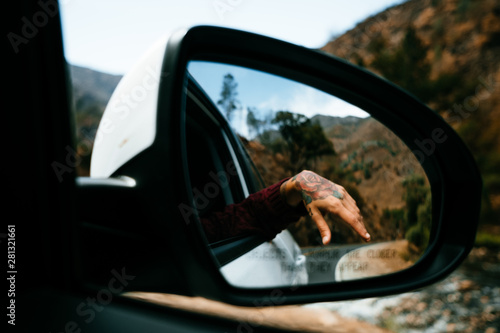 hand with tattoo seen from the rear-view mirror photo