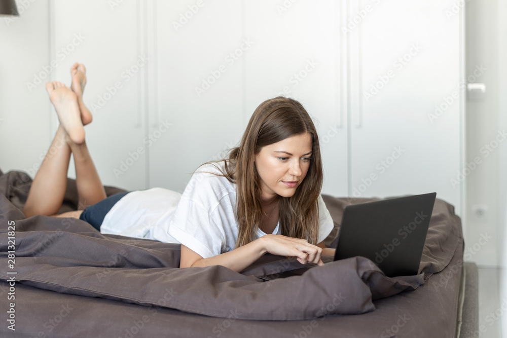 Young adult woman using laptop in bed Young adult woman using laptop in bed
