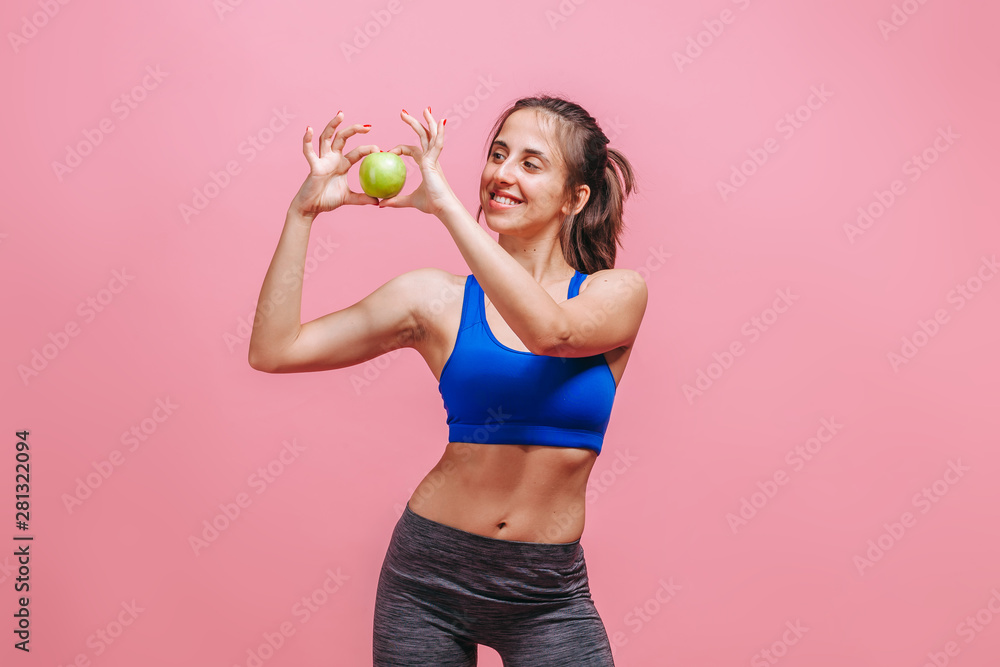 Skinny girl holding green Apple on pink background Skinny girl holding green Apple on pink background