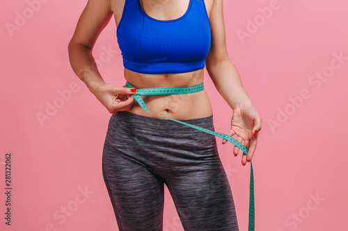 girl measures a waist on a pink background