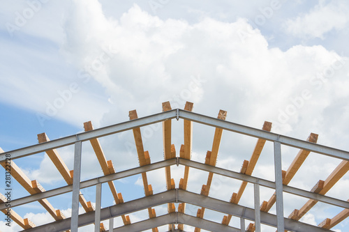 Wooden beams on the metal frame of the building against the blue sky. Roofing during the construction of the hangar.