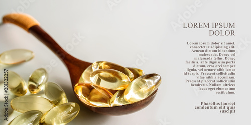 Yellow gelatin capsules with a  drug Omega-3, in a wooden spoon, on a white  background. Alternative treatment, beneficial body support fatty acids for good health