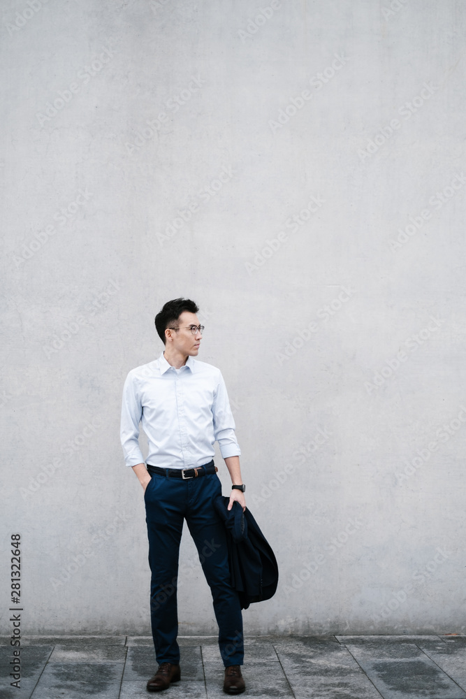 Chinese business man standing by the wall Chinese business man standing by the wall