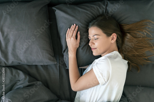 Young adult woman sleeping on bed in morning