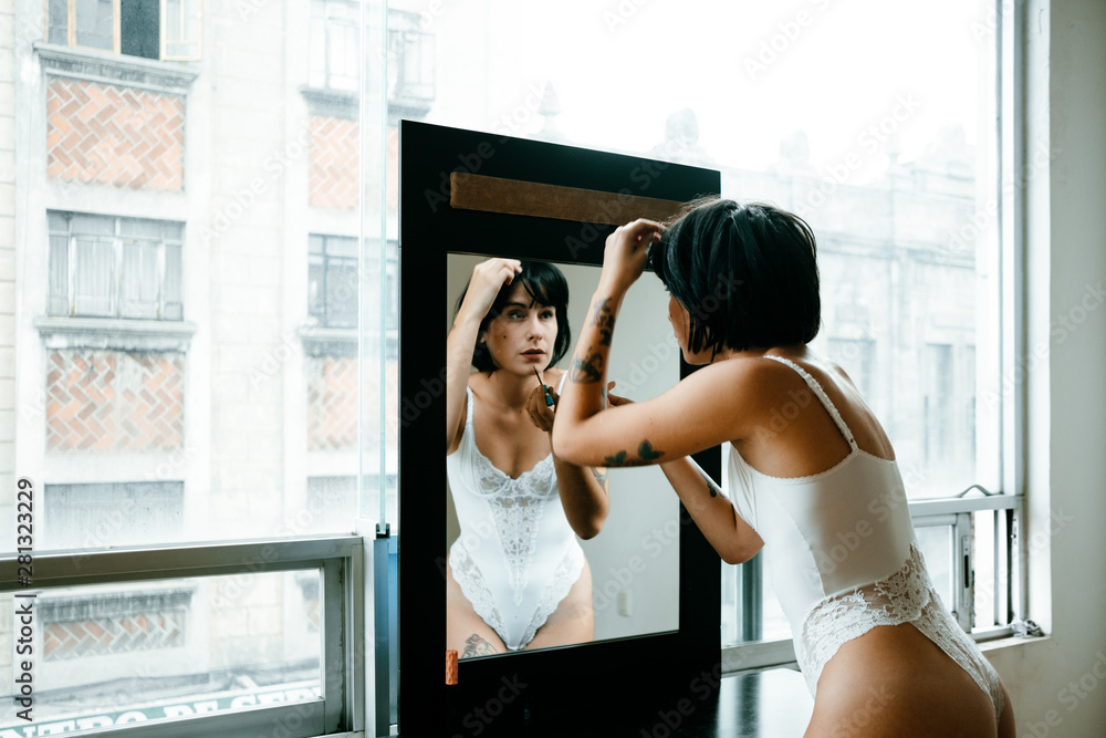 a young brunette girl is preparing in front of the mirror with white lingerie a young brunette girl is preparing in front of the mirror with white lingerie