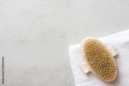 Natural body brush on white pure cotton terry towel on gray marble stone background. Spa wellness skin care anti-cellulites treatment concept