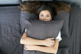 Young adult woman lying on bed and hugging pillow