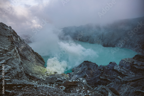 smoking sulfur mine beside acid lake on mount ijen at sunrise photo