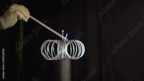 Current line coil sparkles rumble thunder random. man hand metallic part Tesla coil create blue electric arc spark black background 4K. experiment physic static electricity current flow through coil photo