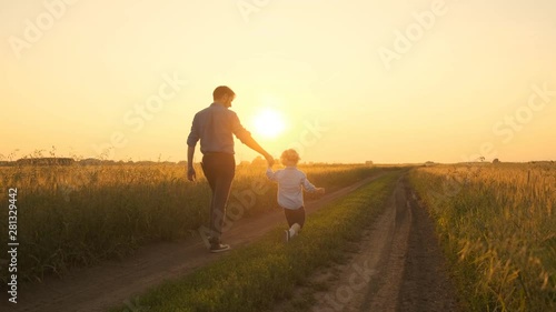 Wallpaper Mural Father and son, father and little boy walking on the field at sunset. Go on the road at sunset in a field. 4k Torontodigital.ca