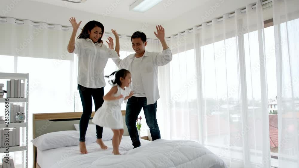 Asian family happy in the house. Father, mother and daughter aged three are jump, dance on the bed. Happiness in the home. Asian family happy in the house. Father, mother and daughter aged three are jump, dance on the bed. Happiness in the home.