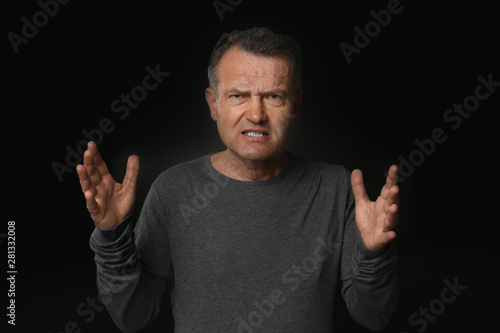 Angry mature man on dark ba...