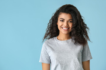 Portrait of cute African-American woman on color background