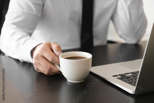 Handsome businessman drinking coffee in office