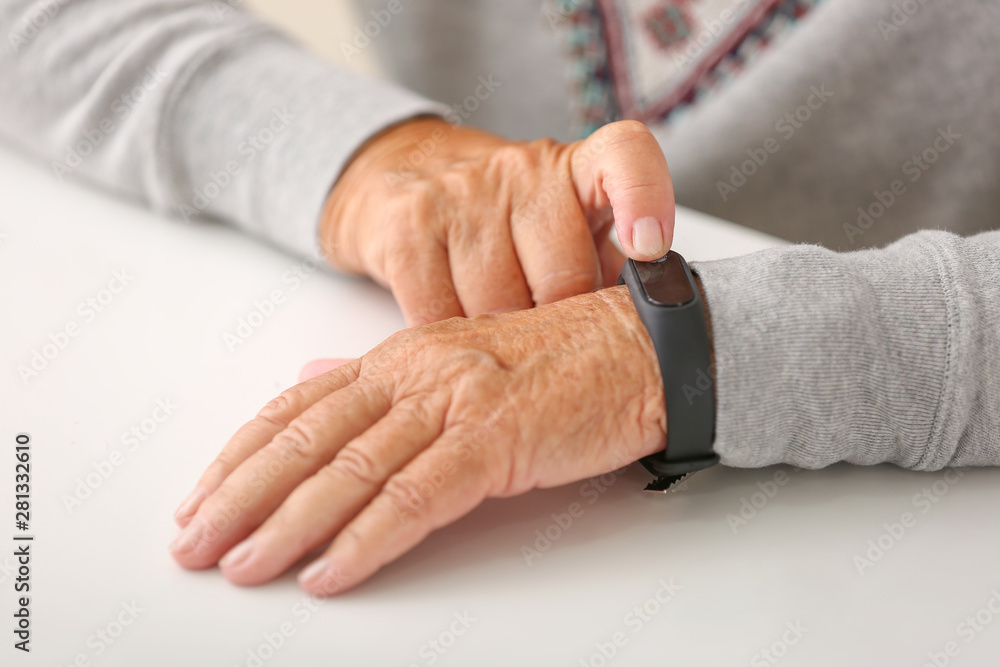 Elderly woman with fitness band checking her pulse, closeup