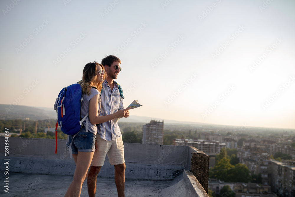 Happy young couple of travellers holding map in hands