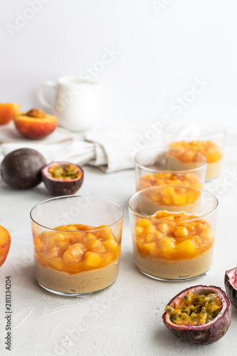 Caramel panna cotta, custard pudding with peach and passion fruit, white table, copy space