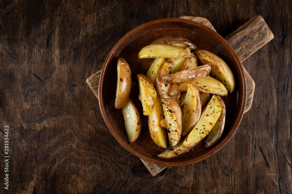 Baked potato in a plate on a wooden background, top view