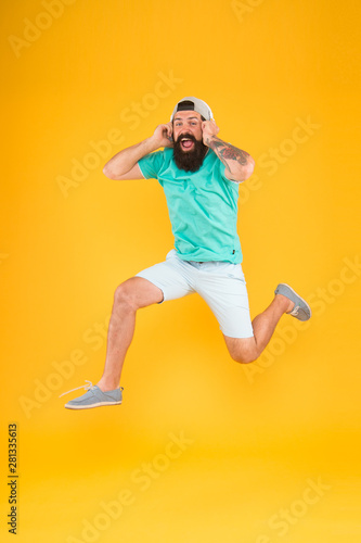 Happy music. Happy hipster jumping on music on yellow background. Bearded man enjoying song playing in headphones with smile on happy face. Happy fun and upbeat