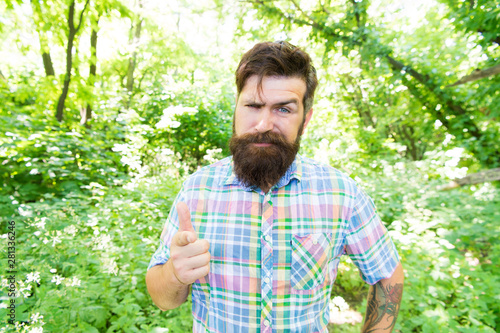 Hey, look. Bearded man pointing finger before him on natural landscape. Brutal hipster pointing with his index finger on camera. Caucasain guy pointing at something. Making pointing gesture © be free