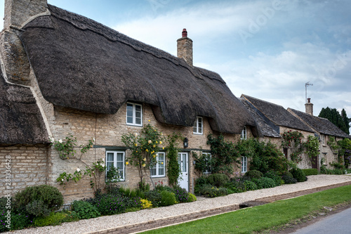 Narrow lane with romantic thatched houses and stone cottages in the lovely Minster Lovell village, Cotswolds, Oxfordshire, England 
