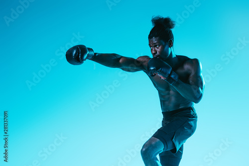 handsome, muscular african american sportsman boxing on blue background © LIGHTFIELD STUDIOS