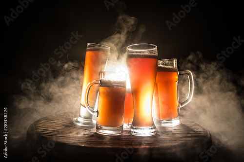 Creative concept. Beer glasses on wooden table at dark toned foggy background.