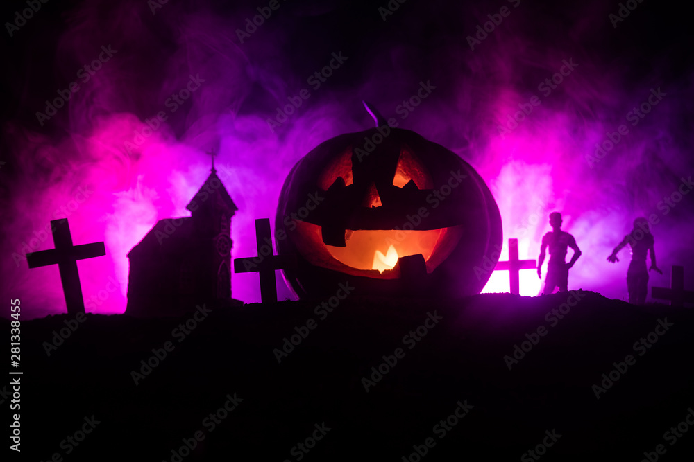 Scary view of zombies at cemetery dead tree, moon, church and spooky cloudy sky with fog, Horror Halloween concept with glowing pumpkin.