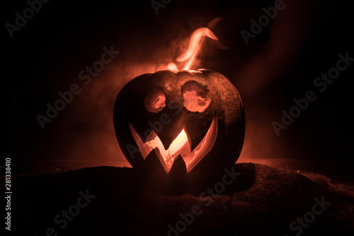 Halloween pumpkin smile and scrary eyes for party night. Close up view of scary Halloween pumpkin with eyes glowing inside at black background. photo