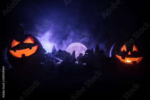 Halloween concept with glowing pumpkins. Strange silhouette in a dark spooky forest at night, mystical landscape surreal lights with creepy man