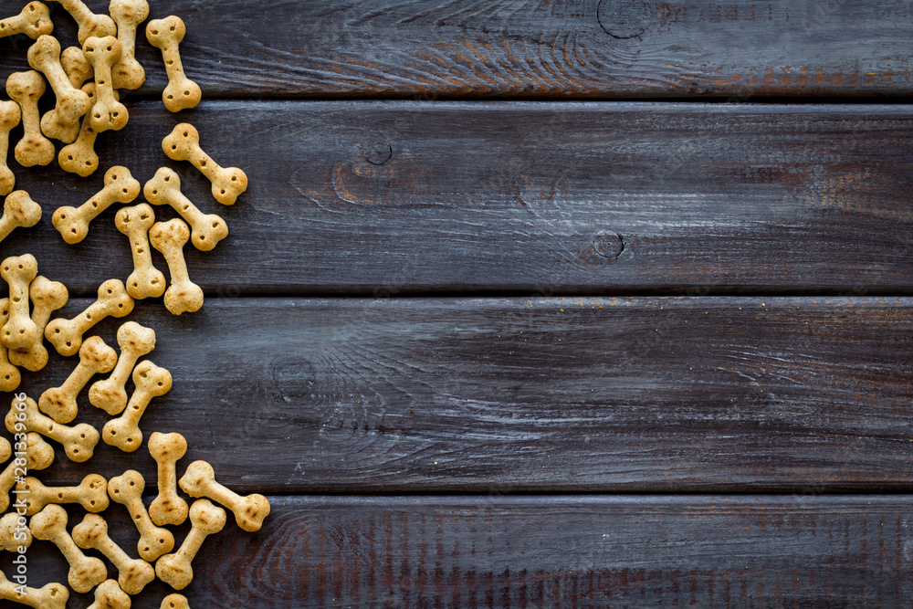 Dry pet food in shape of bone on wooden background top view copyspace Dry pet food in shape of bone on wooden background top view copyspace