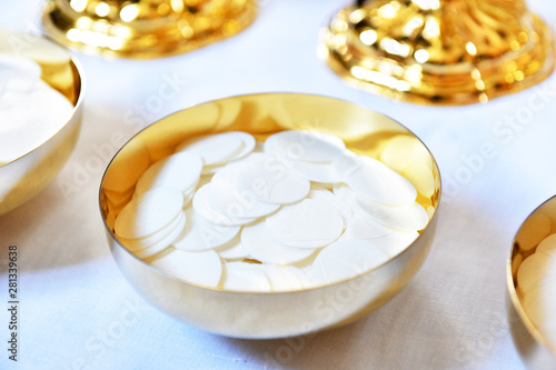 Golden paten with white hosties.