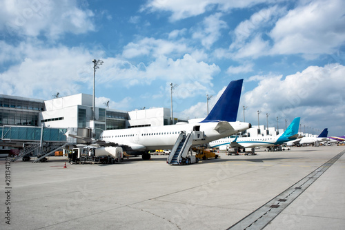 A row of big aircrafts jets at airport under blue cloudy sky.
