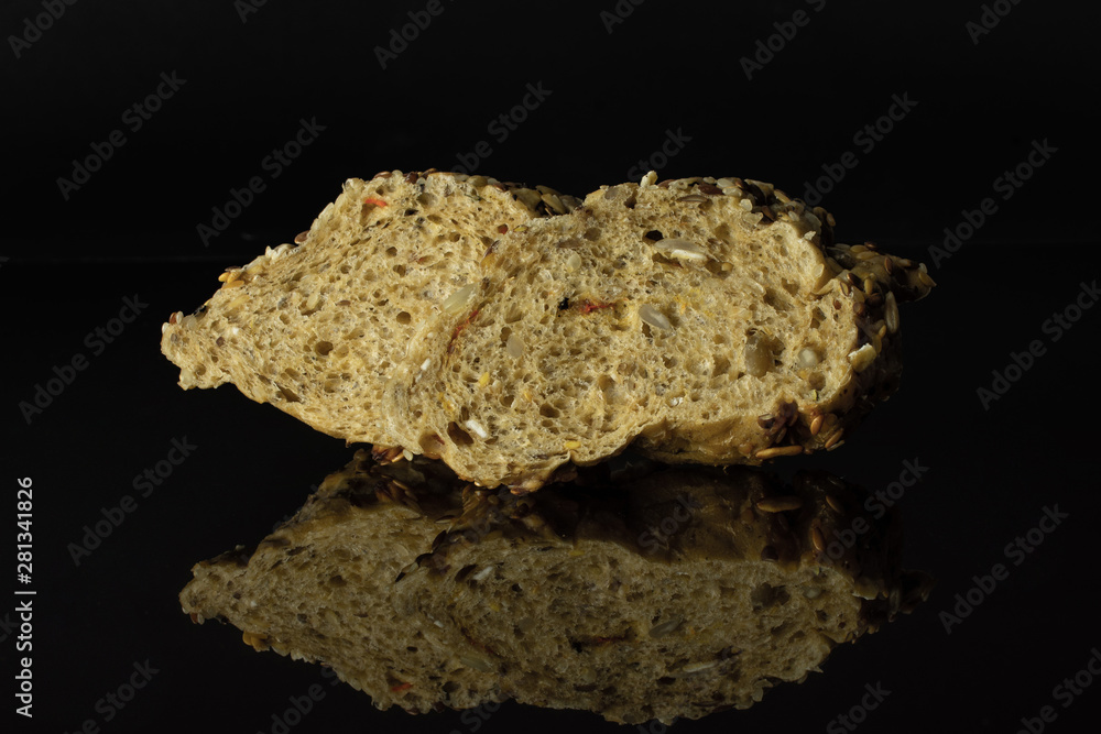 One slice of crumbly fresh cereal baguette isolated on black glass One slice of crumbly fresh cereal baguette isolated on black glass