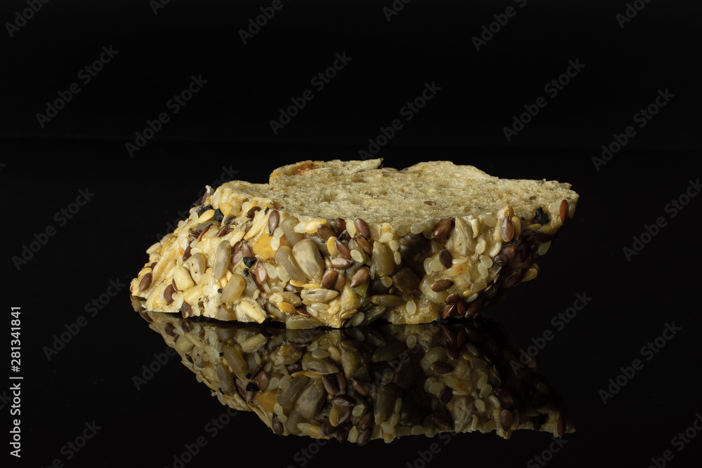 One slice of crispy fresh cereal baguette isolated on black glass One slice of crispy fresh cereal baguette isolated on black glass