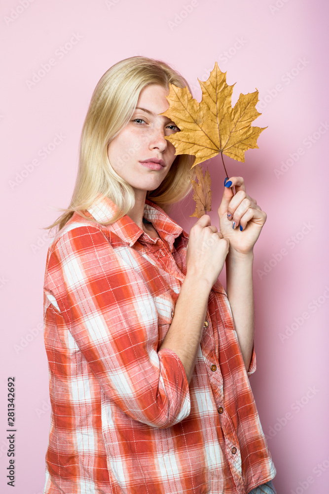 Fototapeta premium Autumn woman. Serious girl in casual wear holds yellow leaves. Fashion trends for fall. Autumn woman with golden maple leaves. Autumn fashion. Blond girl with golden leaf. Autumnal mood. Autumn sales.