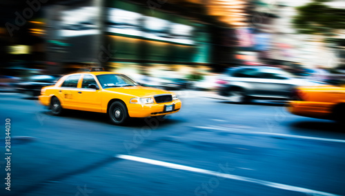 Yellow cab taxi traditional of New York City in fast movement with motion blur panning, in the busy streets of Manhattan, accelerating traffic moves during evening.