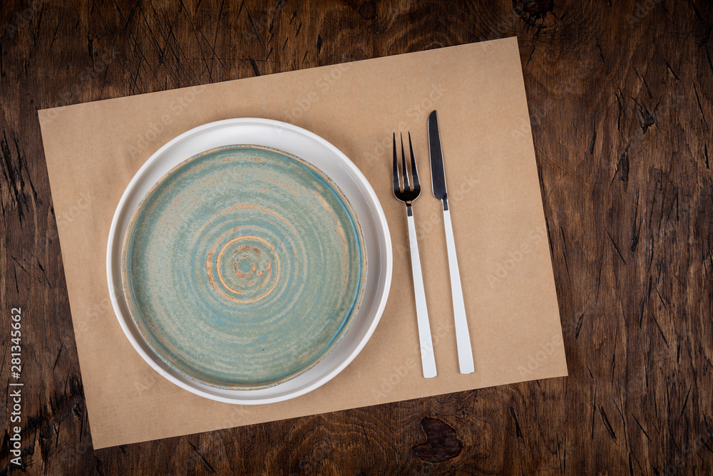 Empty plate with fork and knife on colored wooden background, top view, copy space, mock-up