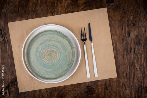 Empty plate with fork and knife on colored wooden background, top view, copy space, mock-up