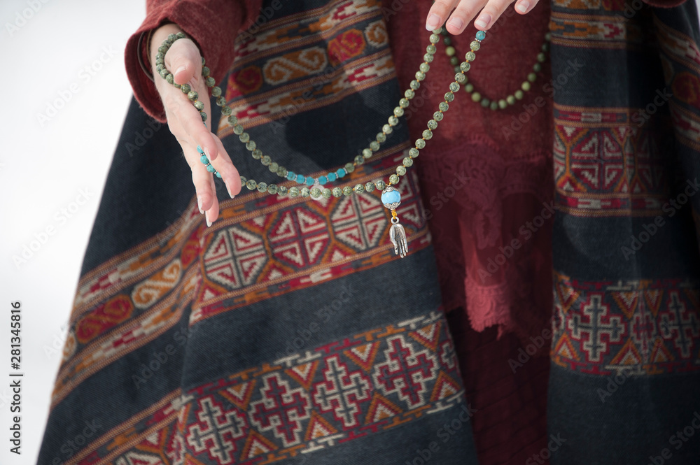 The hands of a woman holding a mala prayer necklace. 